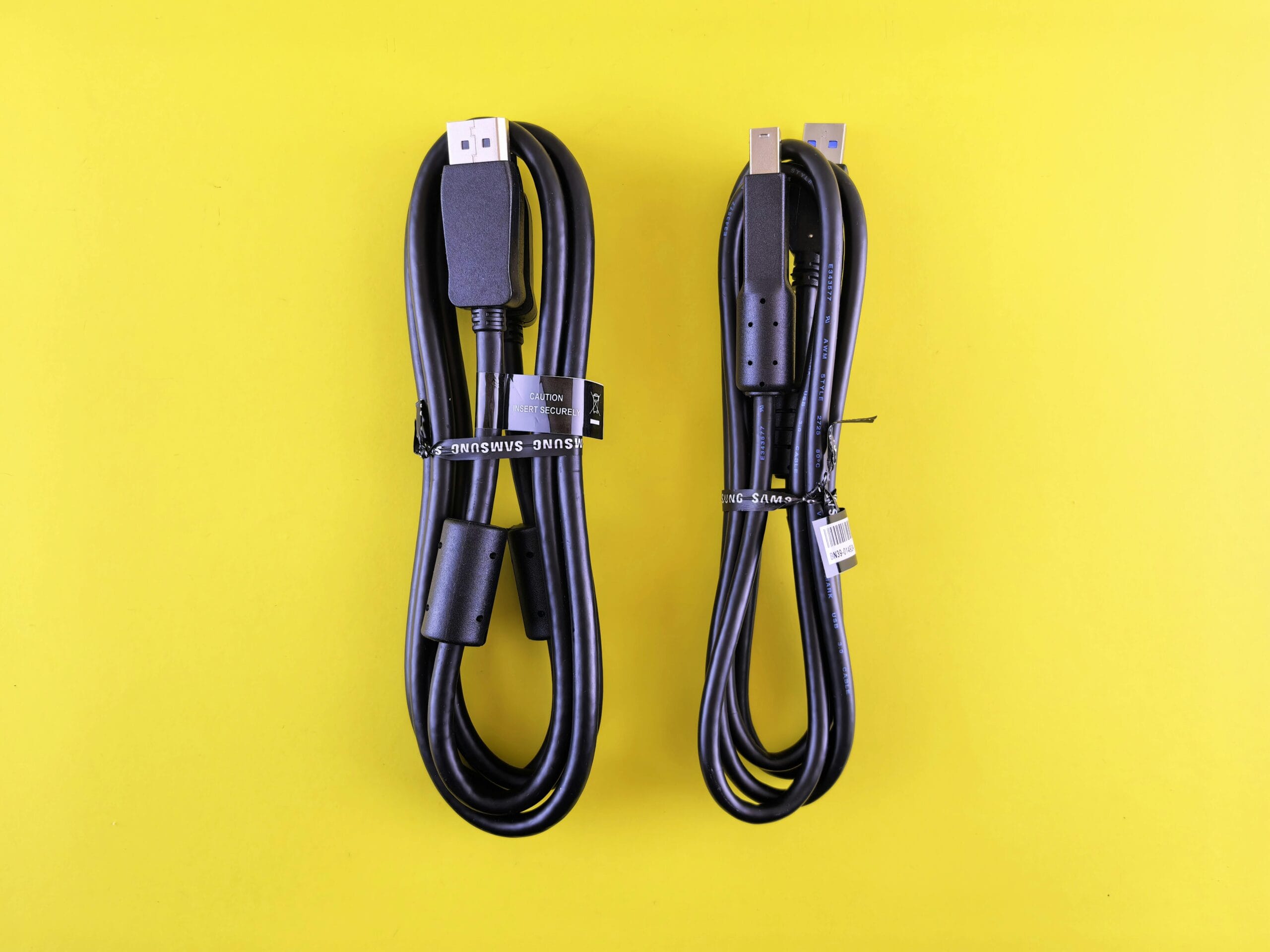 Pair of black Samsung USB cables neatly arranged on a vibrant yellow surface.